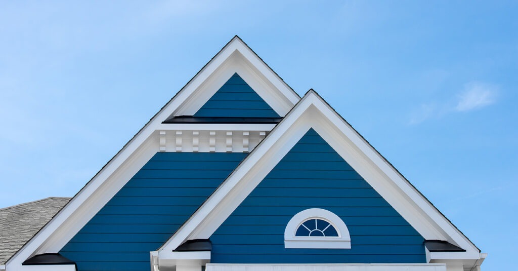 wood looking vinyl white trim roof decoration gable, corbel, louver with pacific blue horizontal siding on a luxury American single family home in the East Coast USA with blue sky background