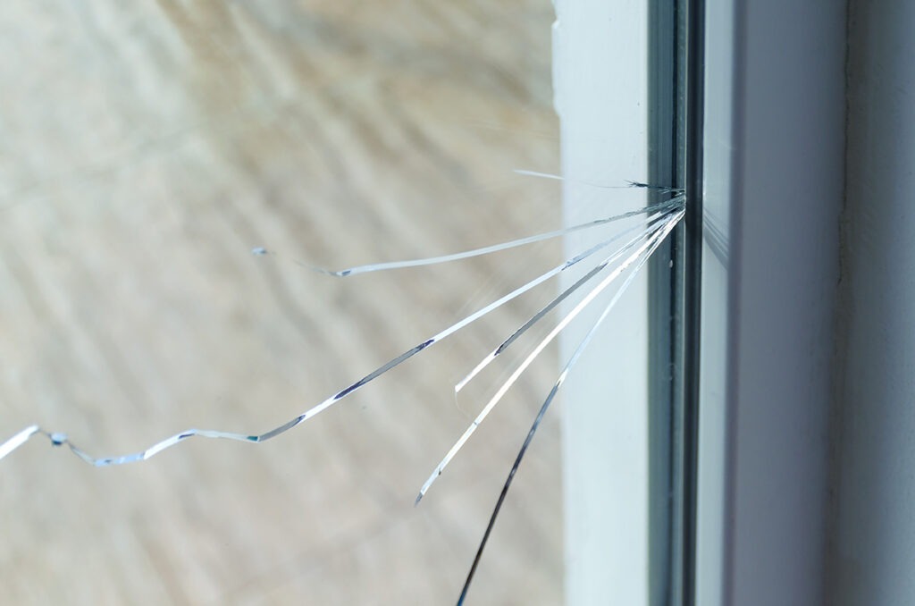 Crack on the glass at a residential house. Plastic window is damaged by cracks.