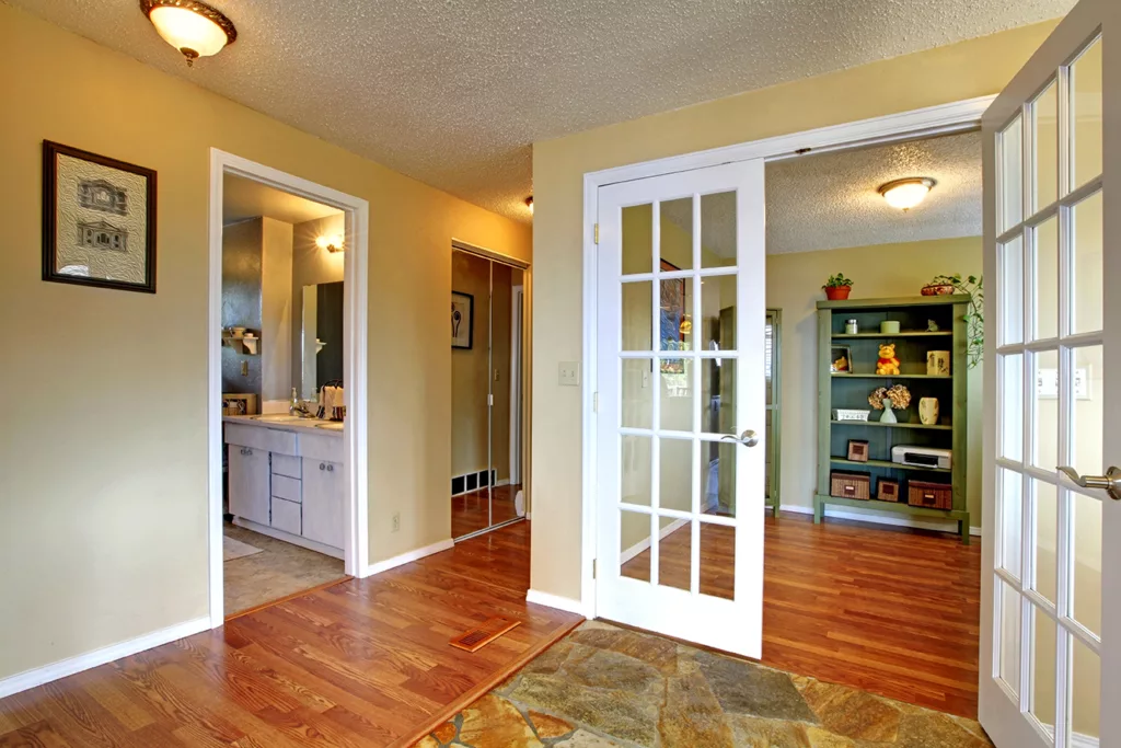 Entrance hallway with stone tile floor. View of office room through open french door